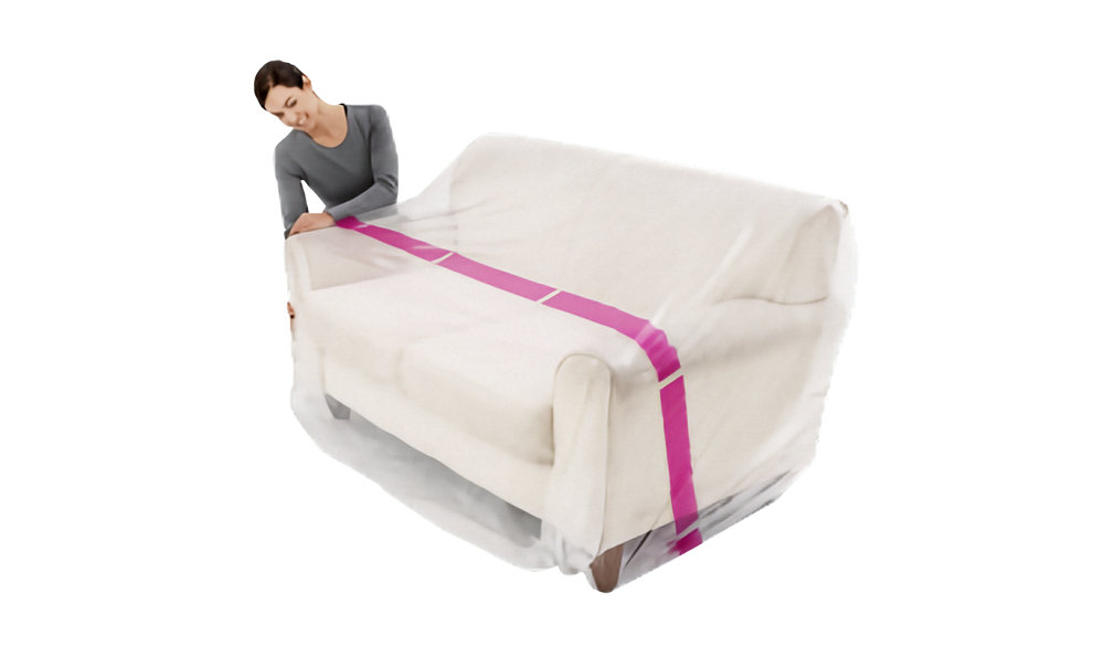 A woman is shown from the side as she drapes a clear plastic sofa cover over a cream-colored seat, secured with bright pink stripe, on a solid white background.
