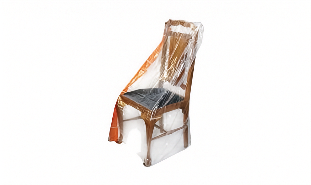 A wooden dining chair with a black seat cushion, wrapped in a clear plastic protective cover, shown against a plain white background.