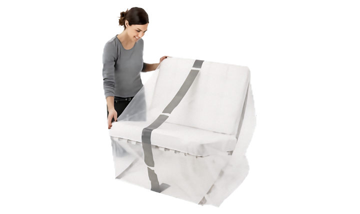 A woman in a gray long-sleeve top and black pants is holding a clear protective lounge cover with gray stripe over a chair, shown against a plain white background.